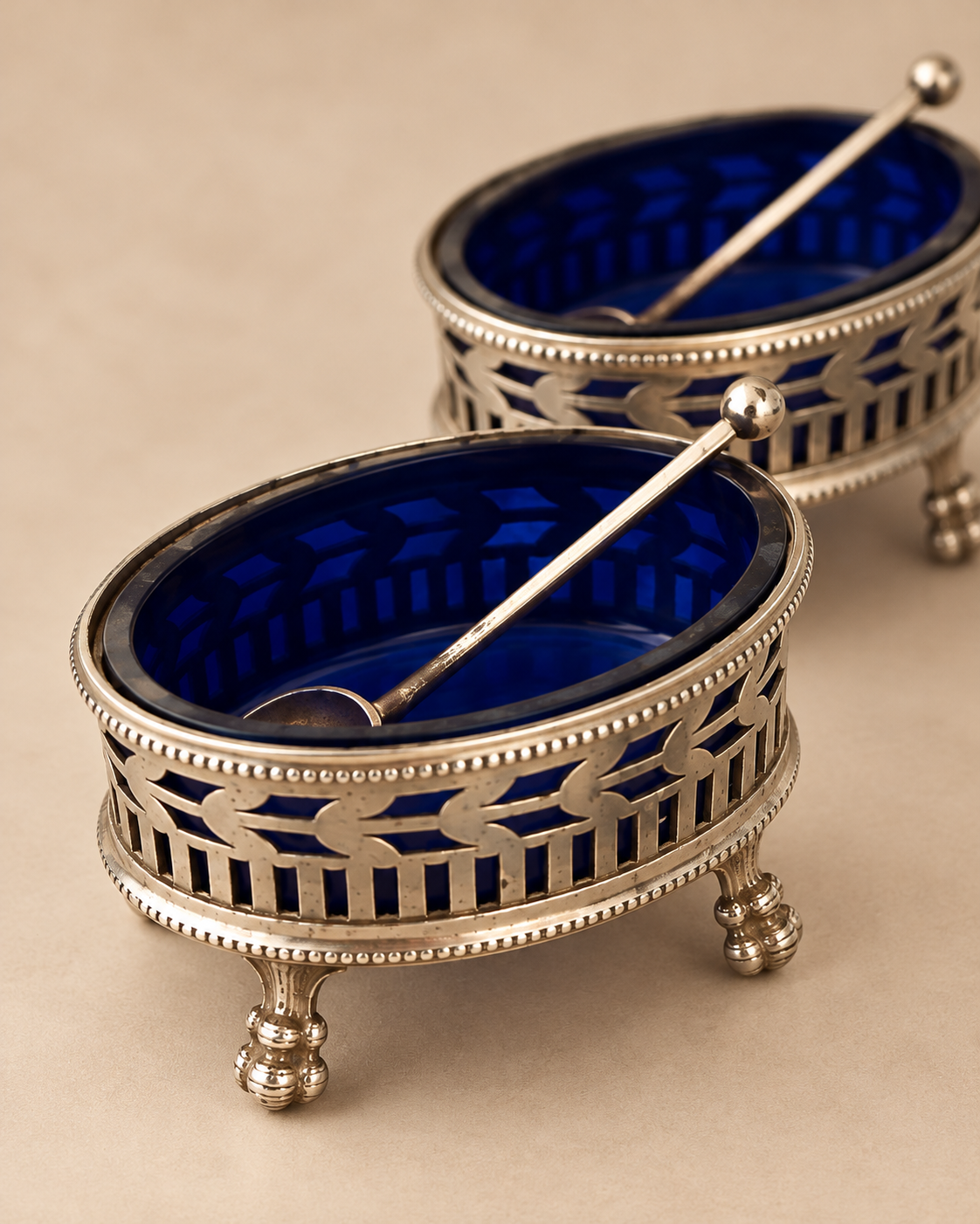 Close-up of a J.M. van Kempen silver salt cellar with cobalt liner and ball-topped spoon, second cellar behind