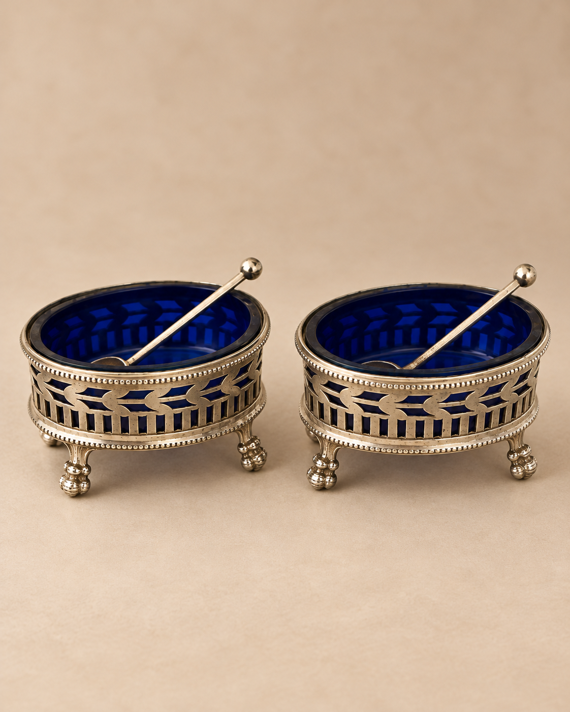 Front view of a pair of Dutch silver salt cellars with pierced leaf galleries, cobalt glass liners and spoons